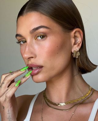 A photo of Hailey Bieber wearing gold eyeliner and a gold chain necklace.