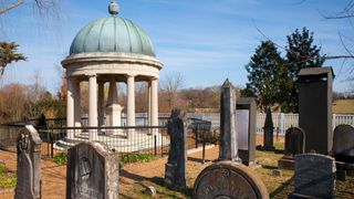 Andrew Jackson's rotunda tomb is surrounded by a low black metal fence along with other standing stones in a cemetery at his plantation, The Hermitage