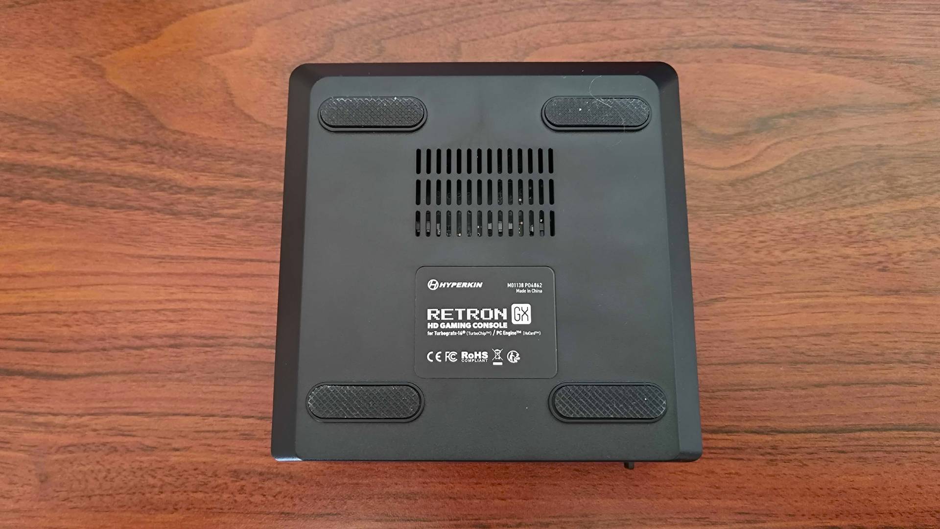 Hyperkin Retron GX with bottom facing upwards on woodgrain desk.