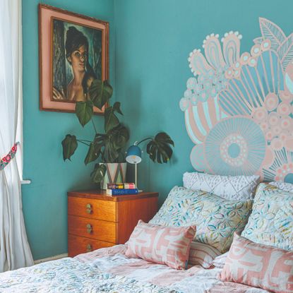 A turquoise blue-painted bedroom with a floral mural painted above the bed