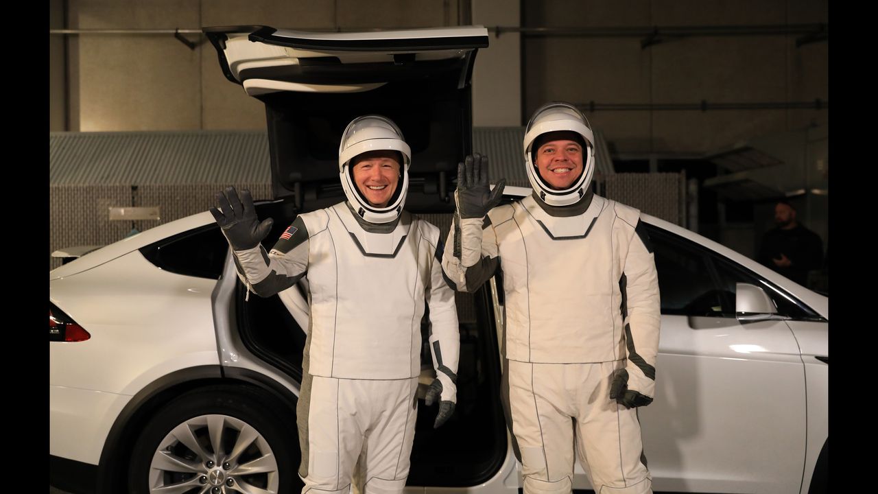 NASA astronauts Doug Hurley, left, and Bob Behnken, wearing SpaceX spacesuits, wave after walking out of the Neil A. Armstrong Operations and Checkout Building at Kennedy Space Center in Florida on Jan. 17, 2020, during a dress rehearsal ahead of the SpaceX uncrewed In-Flight Abort Test. A SpaceX Falcon 9 rocket and Crew Dragon spacecraft will lift off from Launch Complex 39A on the flight test, which will demonstrate the spacecraft&rsquo;s escape capabilities in preparation for crewed flights to the International Space Station as part of the agency&rsquo;s Commercial Crew Program. Behnken and Hurley are slated to fly on the company&rsquo;s first crewed mission, Demo-2.