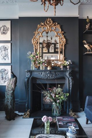 A decorated black living room with black walls, golden ornate mirror and a peacock decorative on the floor