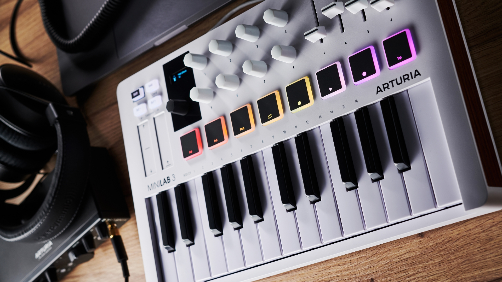 An Arturia Minilab 3 MIDI keyboard on a desk with various bits of home recording gear