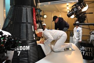 Mercury astronaut John Glenn, played by Patrick J. Adams, assists Mercury astronaut Alan Shepard (off camera), portrayed by Jake McDorman, inside the Freedom 7 Mercury capsule, in a behind-the-scenes photo from the season finale of National Geographic's "The Right Stuff," now streaming on Disney+.