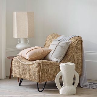 room with a wicker armchair and a lamp on a table