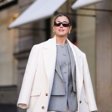 woman wearing grey suit and cream coat