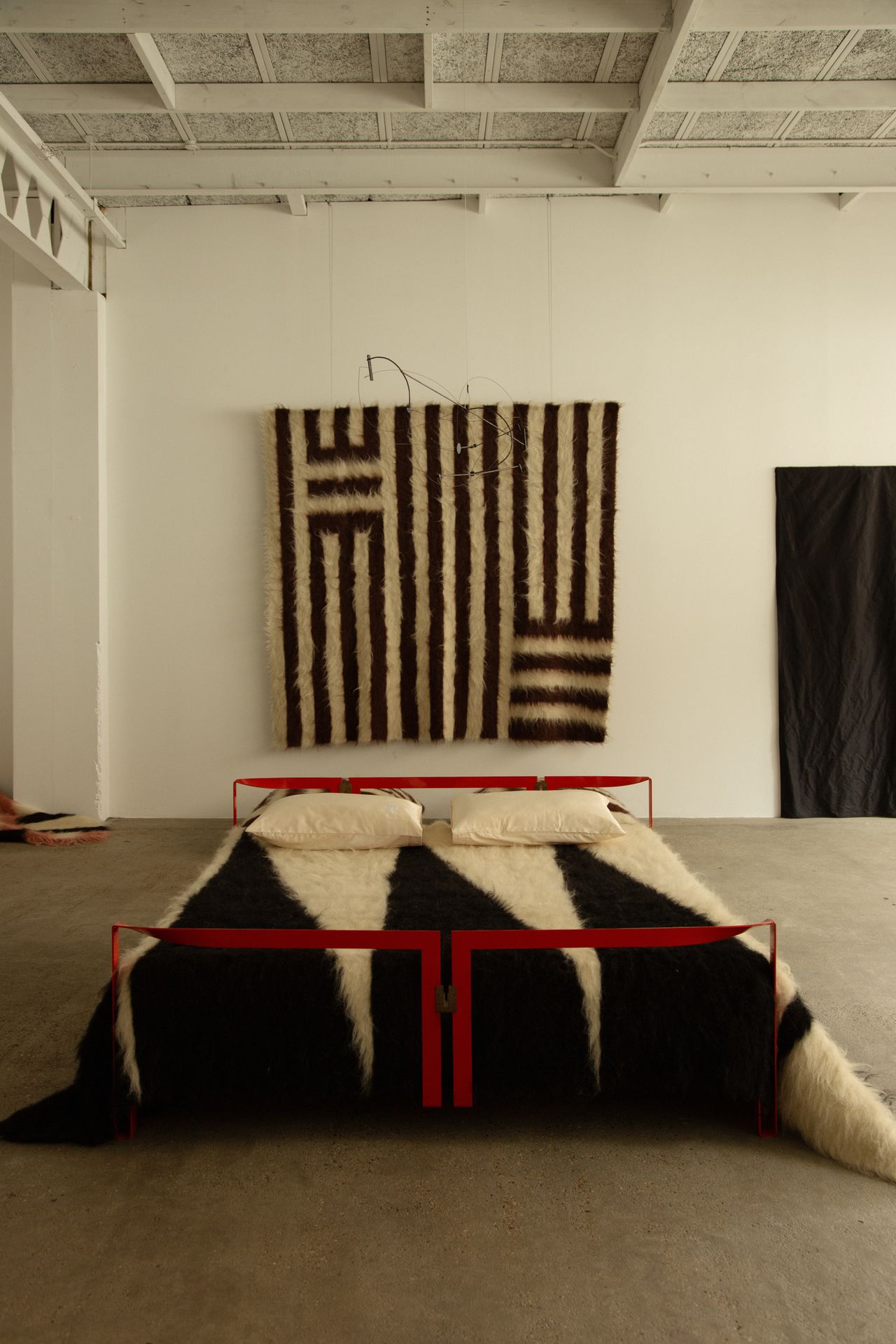 A series of textile creations with an abstract, textural wool feel sit in an industrial showroom alongside iconic modernist designs.