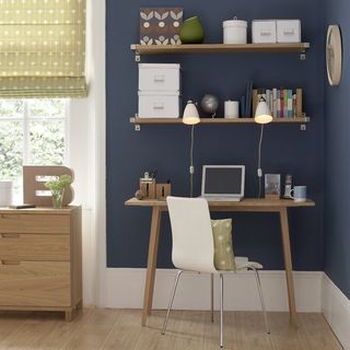 room with navy coloured wall and wooden floor and shelves with desk and chair