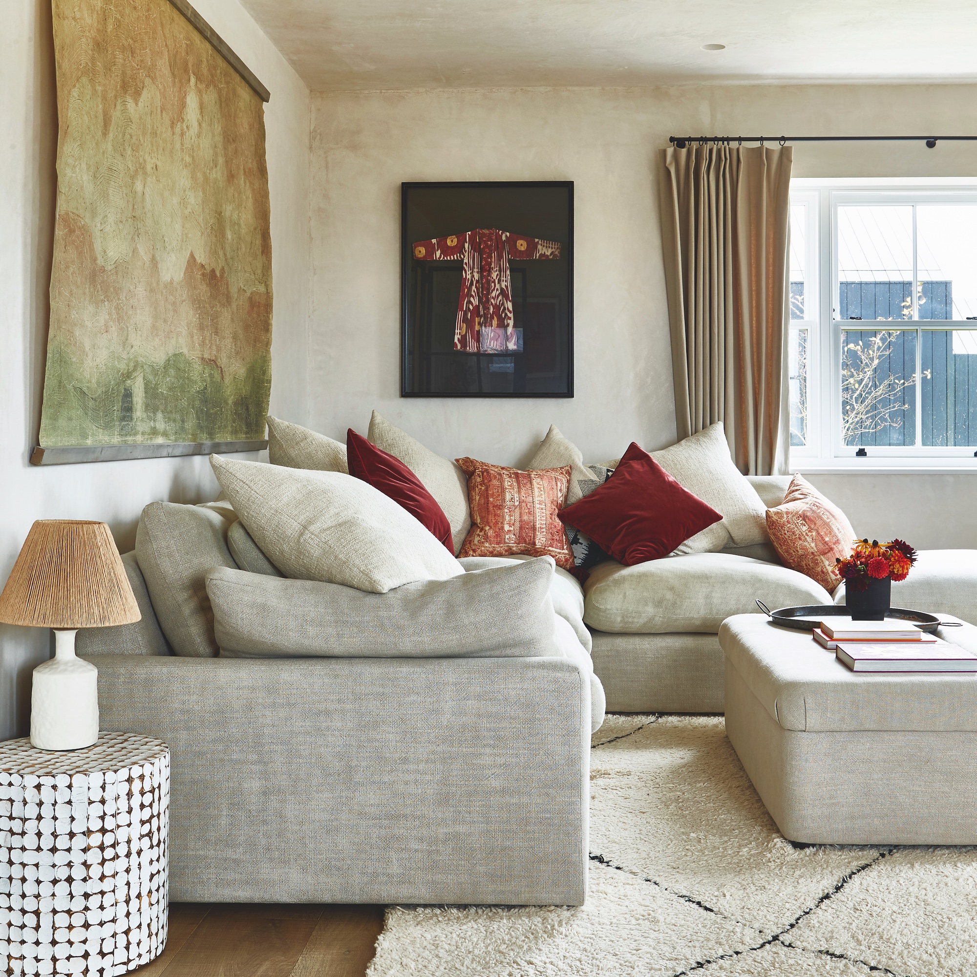 sitting room with corner sofa with throw cushions, rug on floor and upholstered ottoman coffee table