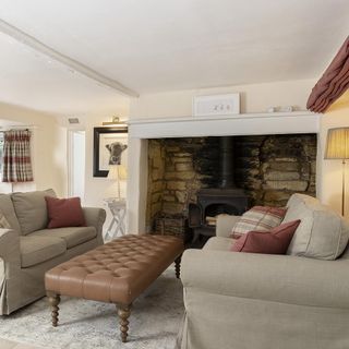 Cotswold cottage's cream and dusty pink living room, with a fireplace and leather coffee table