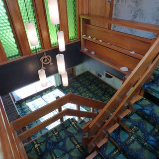 staircase with pendulum light hanging and blue patterned carpet