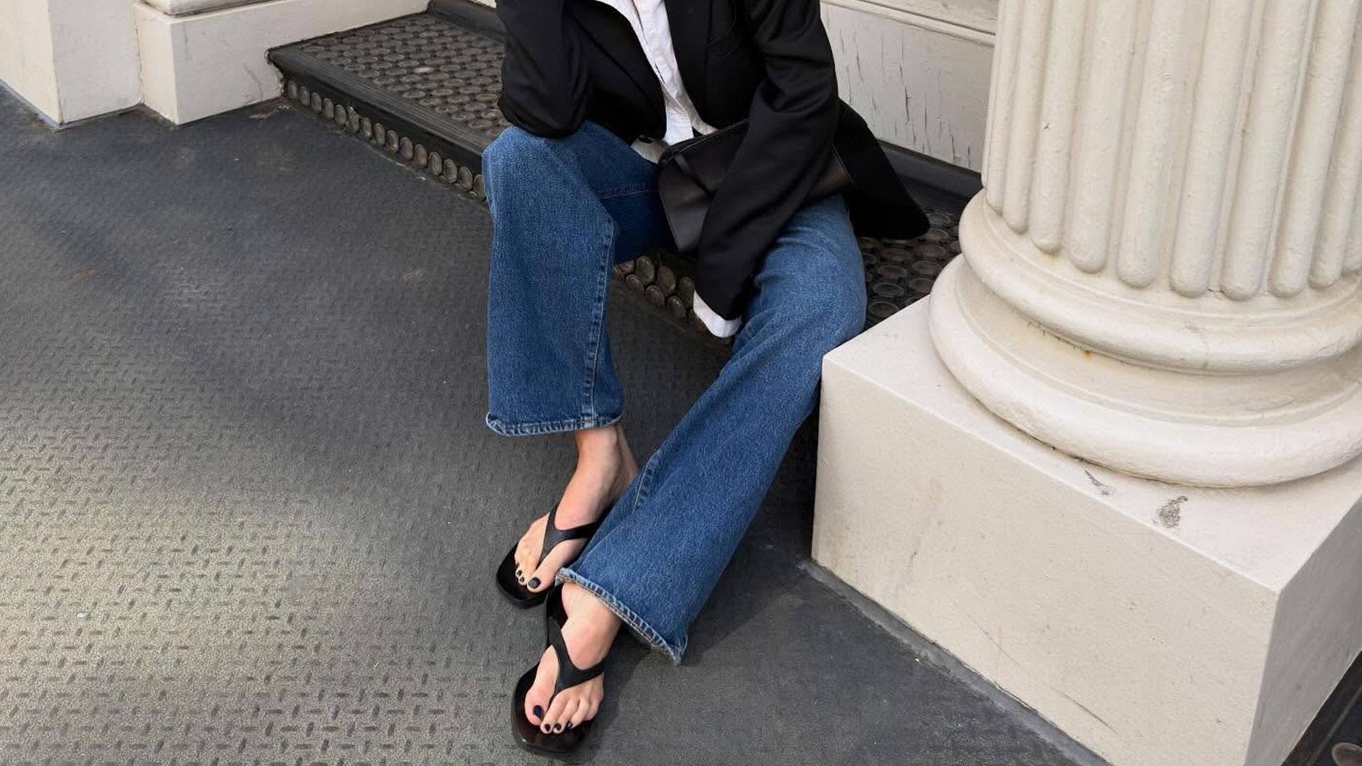 @cocoschiffer seated outfit photo in black blazer, white shirt, jeans, and black filp-flop sandalas