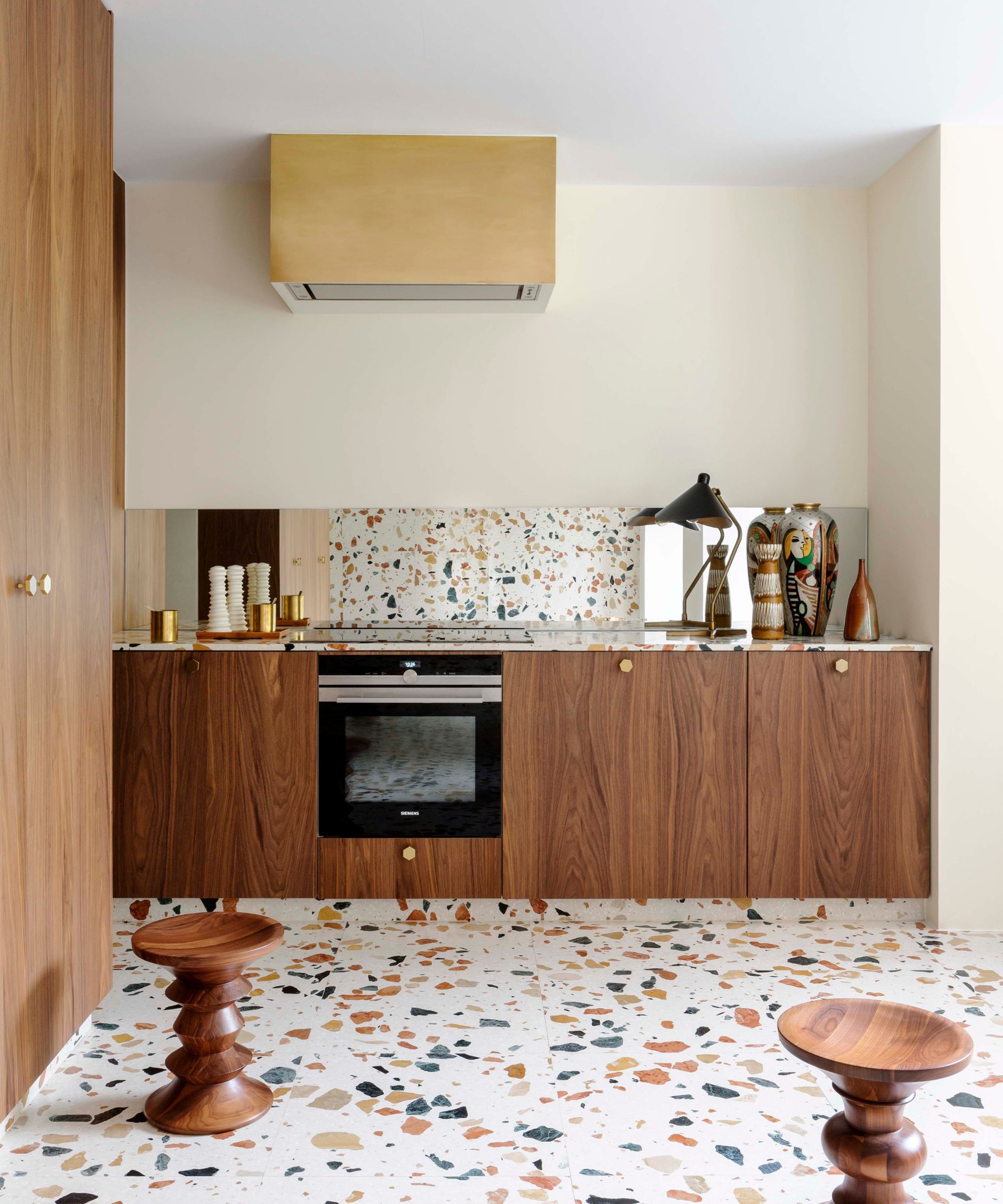 Retro kitchen by Victoria-Maria with walnut cabinets, terrazzo floor and brass cooker hood