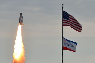 Space shuttle Endeavour appears to fly past flags in the foreground, on its way to the International Space Station. Launch of the STS-134 mission took place at 8:56 a.m. EDT on May 16.
