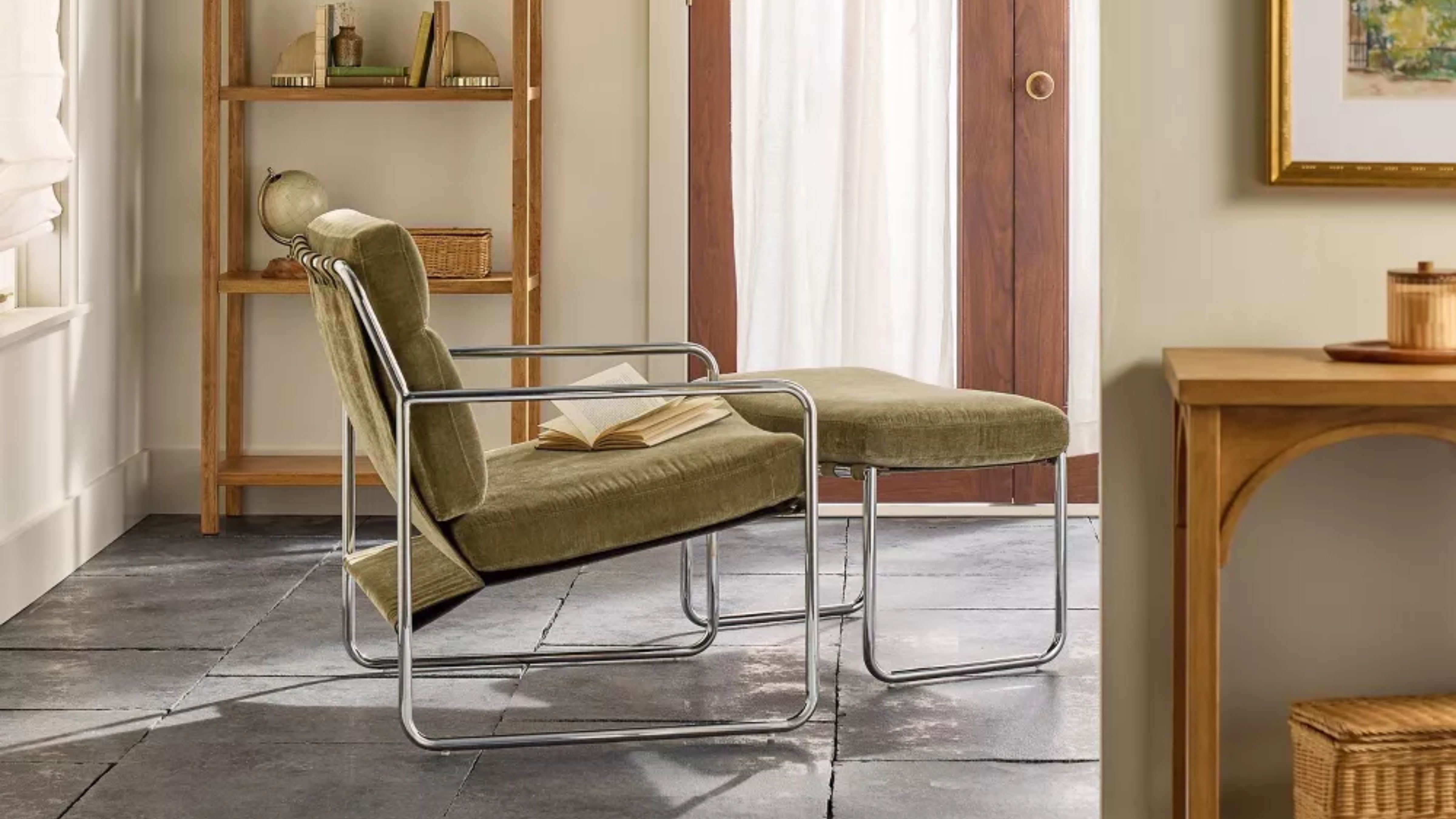 Joanna Gaines' mid-century-style chrome accented, green upholstered armchair and ottoman duo pictured in a sunlit living room flooded with natural light 