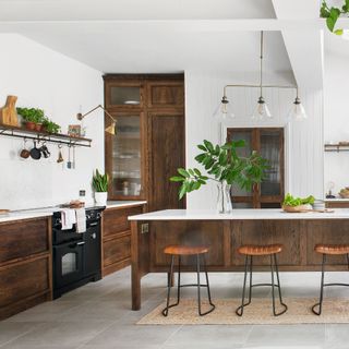 large kitchen with white walls, rustic wood units and island with stools