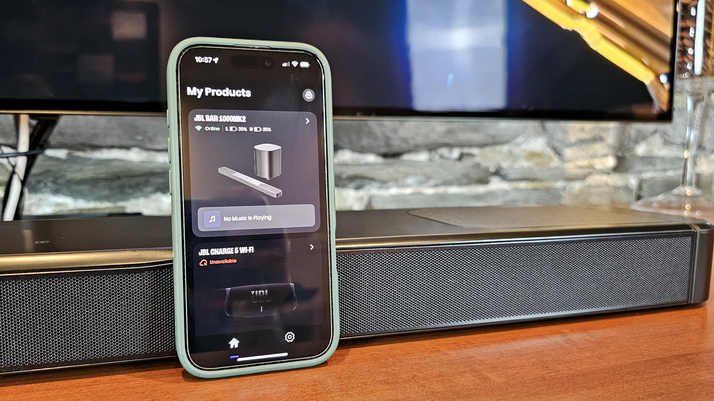 JBL Bar 1000MK2 on TV stand with phone running JBL One app