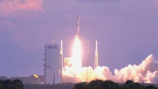 a rocket launch into a early morning sky colored pink and purple.