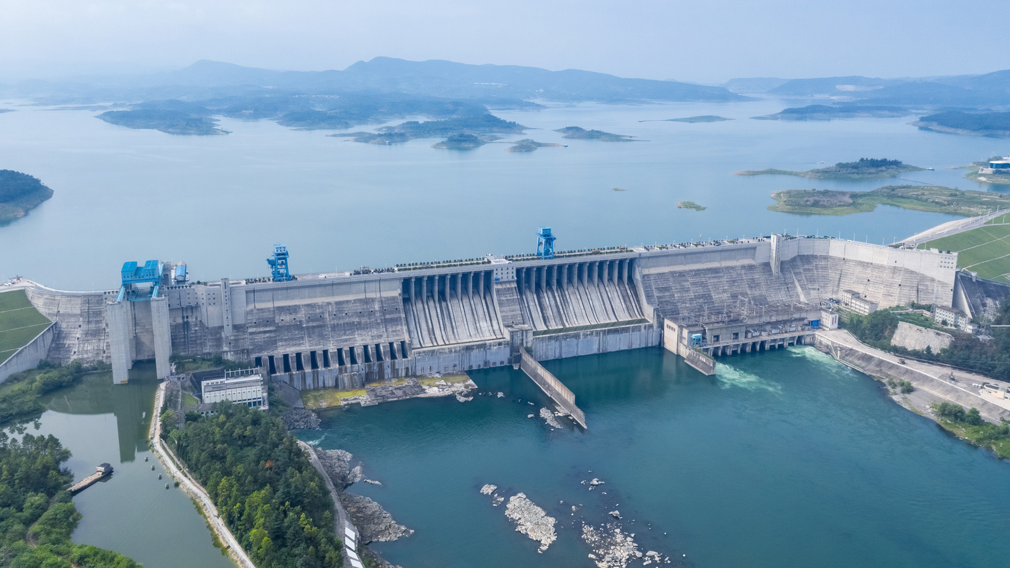 An aerial view of a reservoir with a large concrete dam on one end.