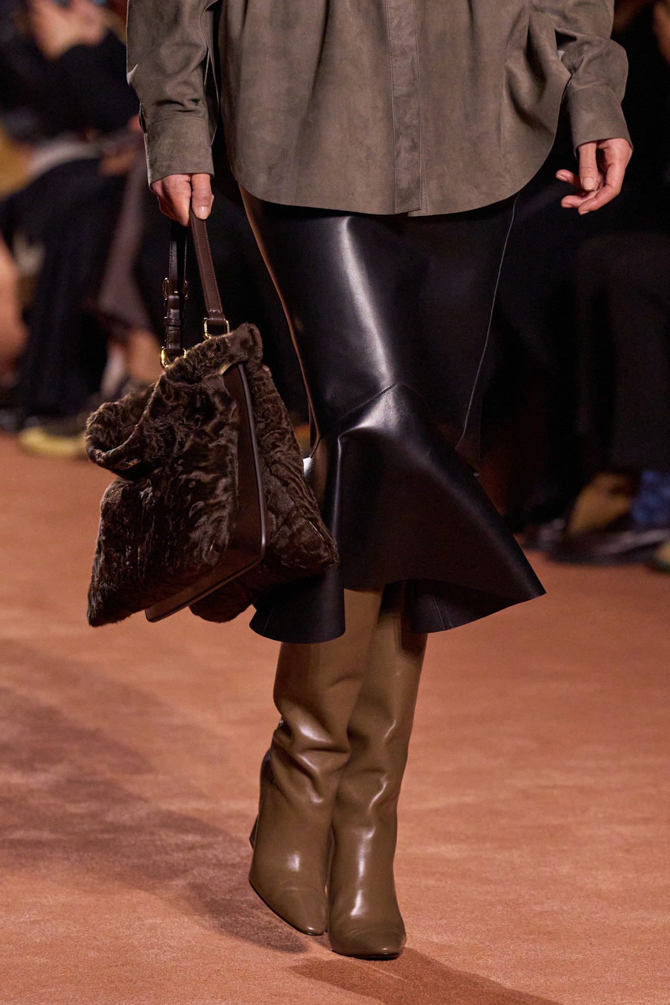 Woman in leather skirt and brown boots.