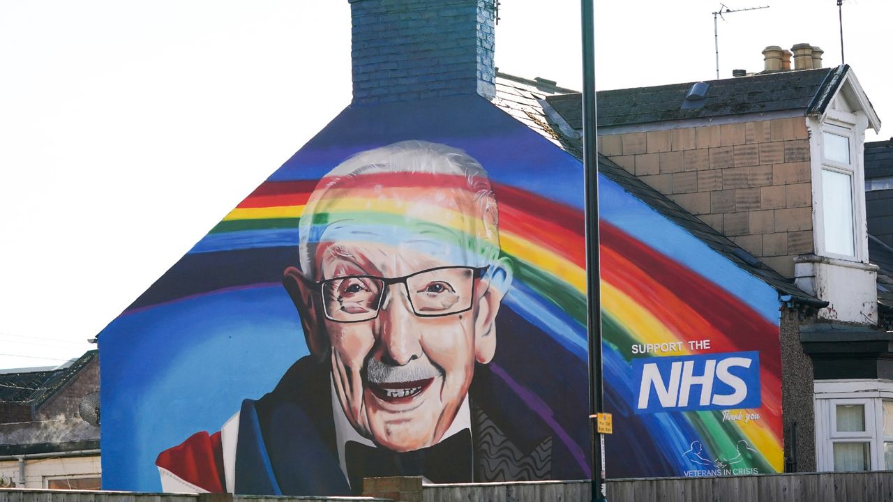 A mural depicting Captain Sir Tom Moore on a wall with a rainbow and a sign for the NHS