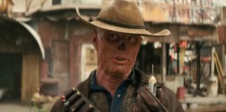 a post-apocalyptic cowboy with no nose displays a tranquilizer dart