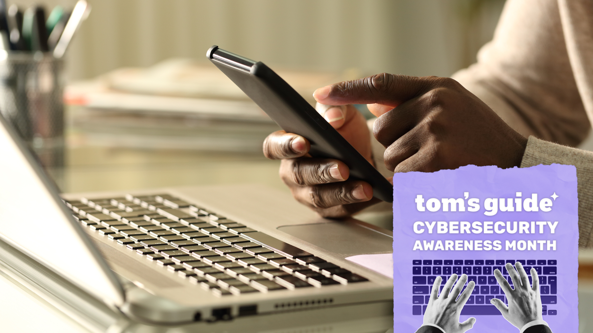 A man on a laptop with a smartphone with a Tom's Guide Cybersecurity Awareness Month badge