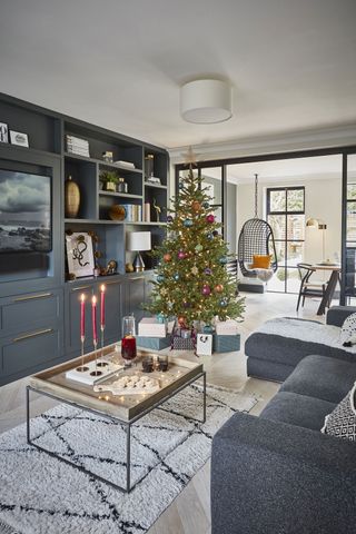 living room with Christmas tree and candlesticks with built in grey shelving