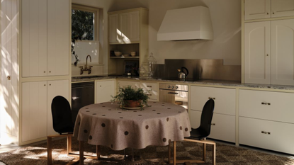 small corner kitchen with white cabinets and yellow trim with a dining table in the middle