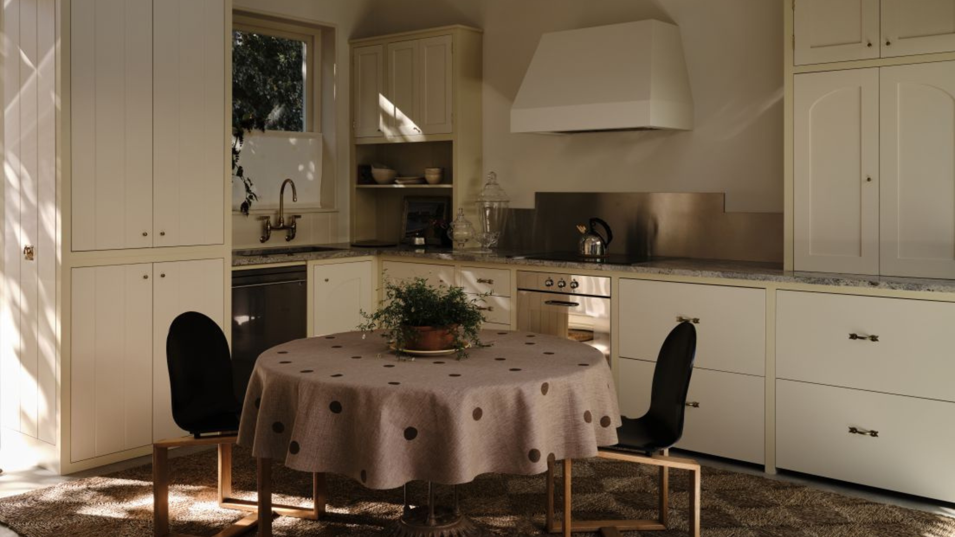 small corner kitchen with white cabinets and yellow trim with a dining table in the middle