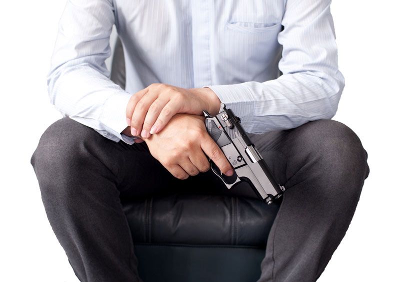 A man in a suit holding a gun.