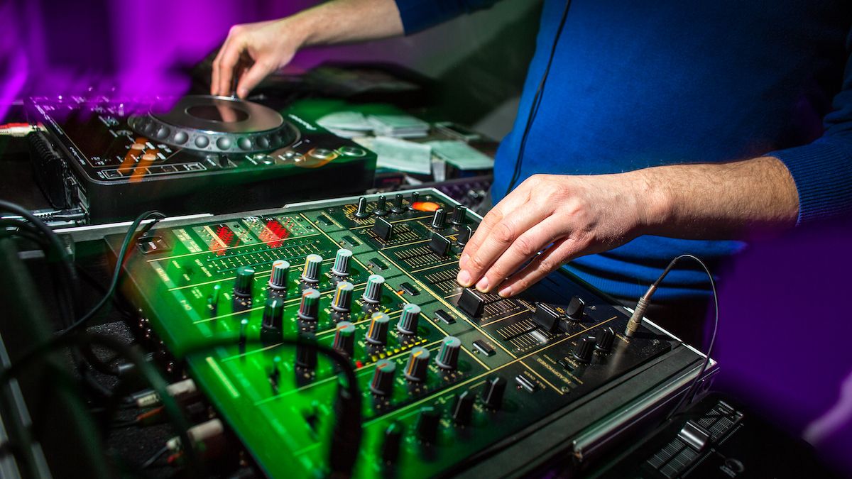 Close-up of hands on a DJ mixer and controller