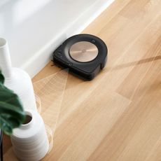 Roomba iRobot s9+ vacuum cleaner in promo image being used on hard floor 