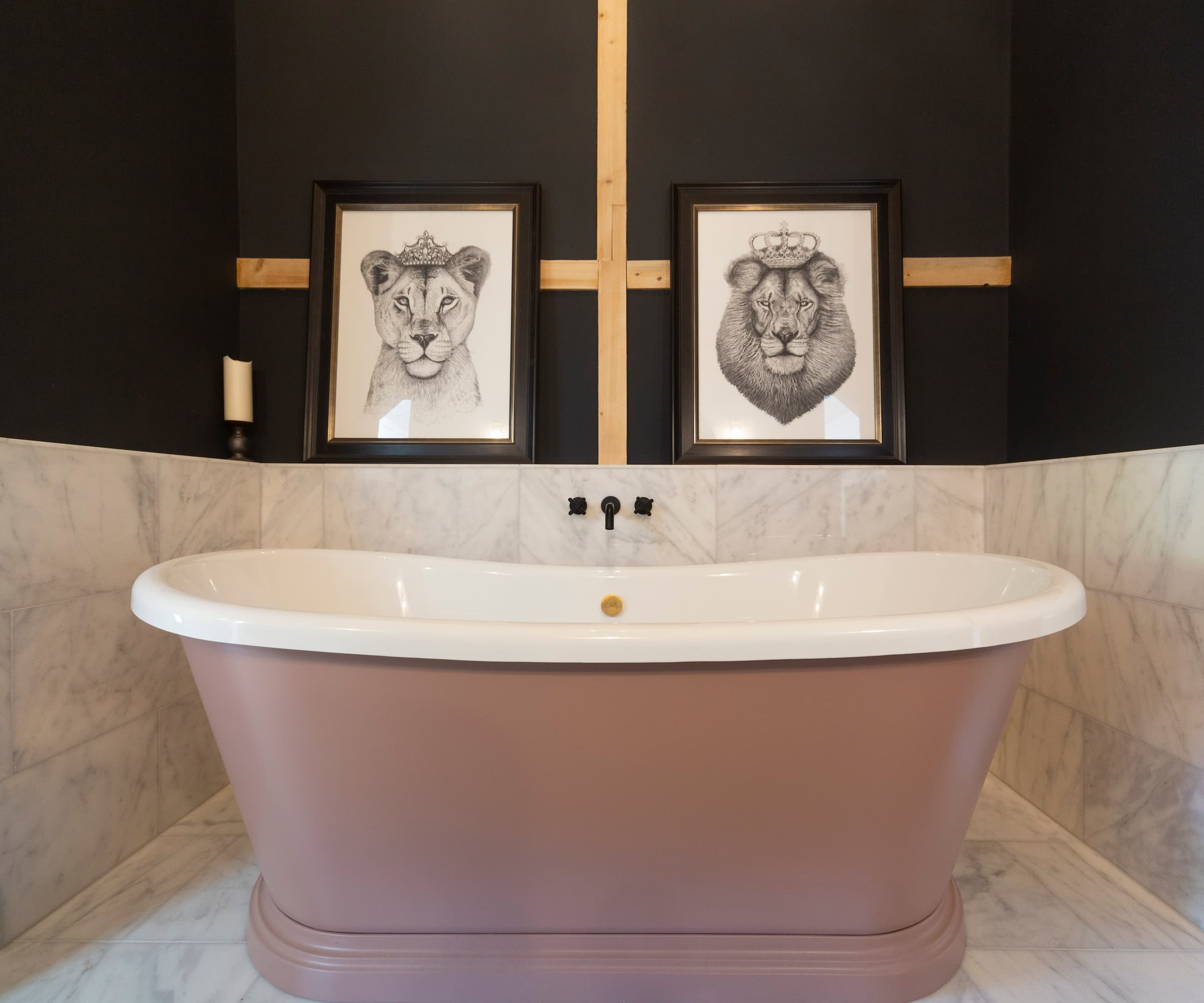 A pink bath with porcelain tiled floors and walls with a picture of a lion and lioness each wearing crowns