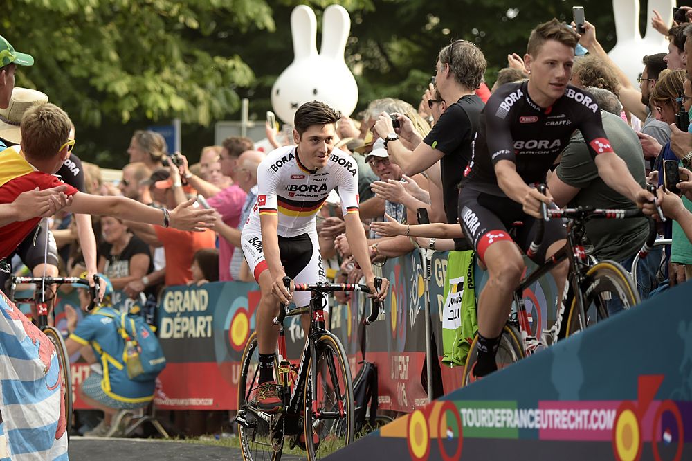 Germany's Emanuel Buchmann (L) rides towards the stage for the team presentation ceremony at Lepelenburg Park