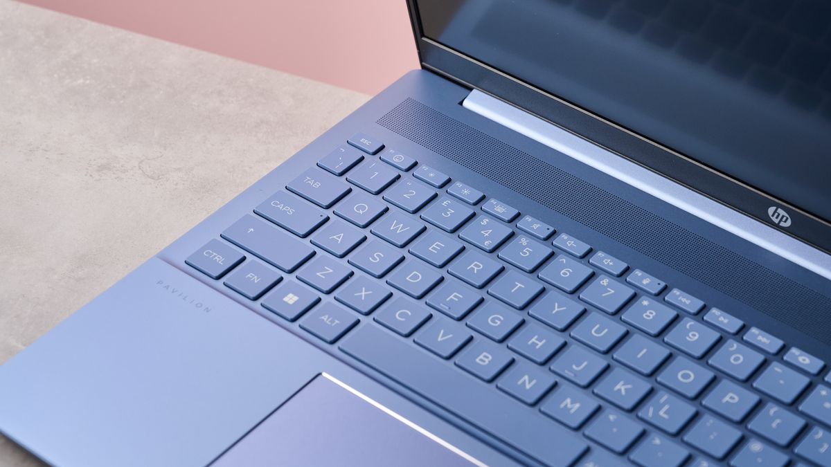 Close-up of keyboard on HP Pavilion 16, on desk with pink wall in background