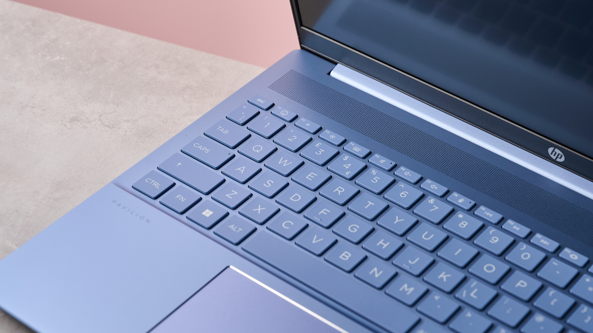 Close-up of keyboard on HP Pavilion 16, on desk with pink wall in background