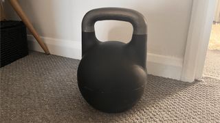 Kettlebell Kings Adjustable Competition Style Kettlebell on a carpeted floor