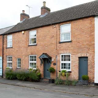 house exterior with bricked wall and grey door and road