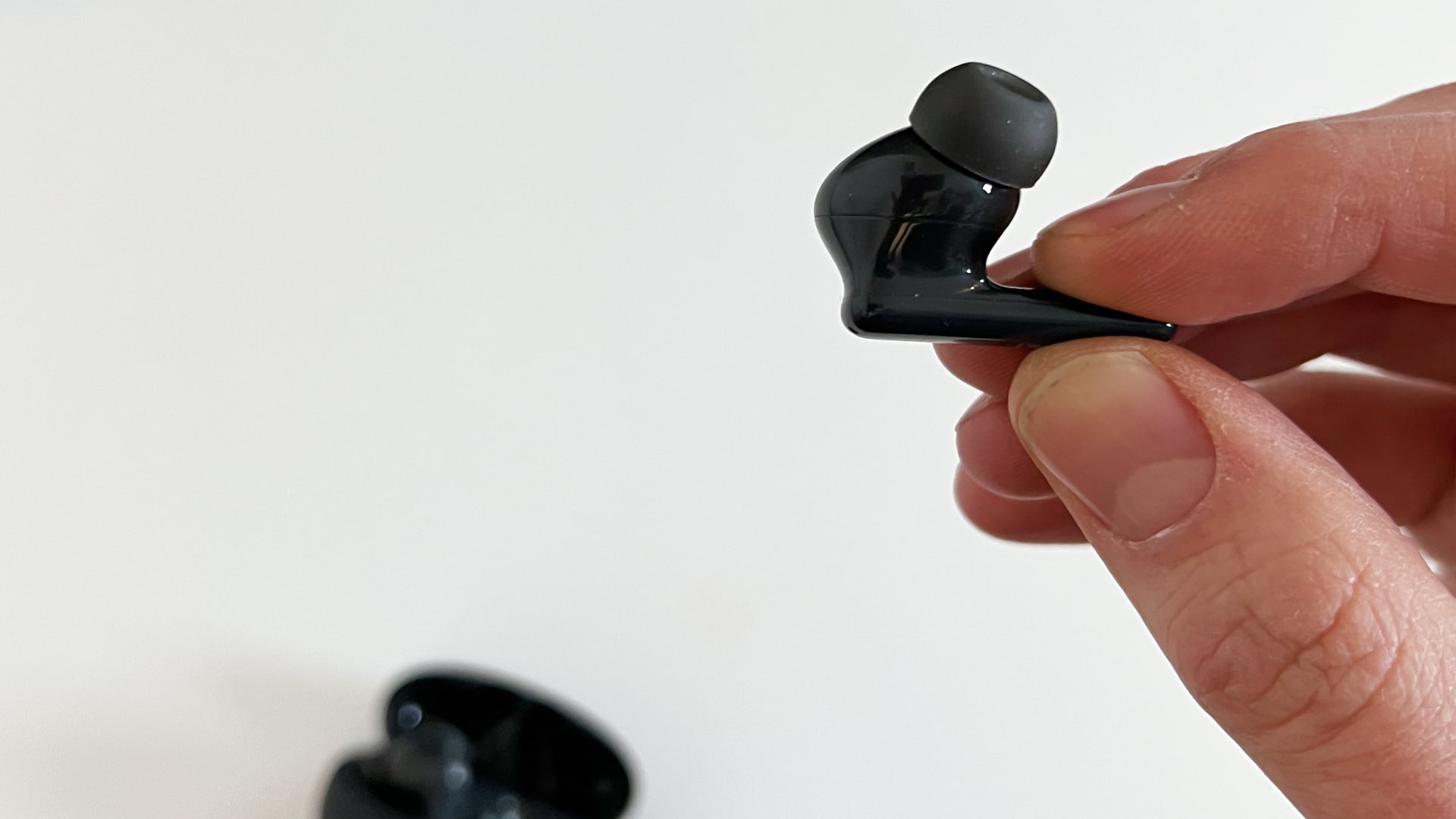 Helt trådløse ørepropper av typen Huawei Freebuds 5i i en hånd mot en hvit bakgrunn.
