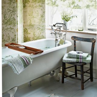 bathroom with green patterned wallpaper and bathtub