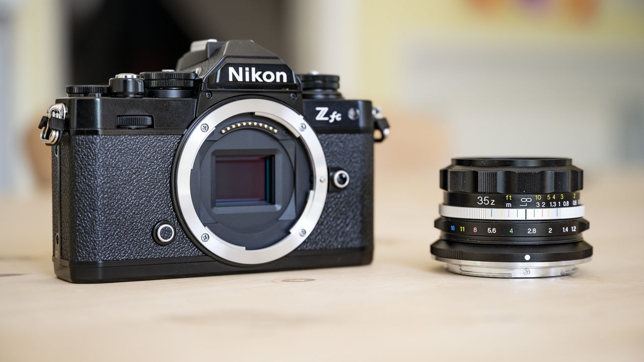 Voigtlander D 35mm f1.2 Nokton lens on a wooden table alongside a Nikon Z fc