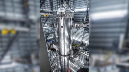 a tall silver rocket upright in a hangar