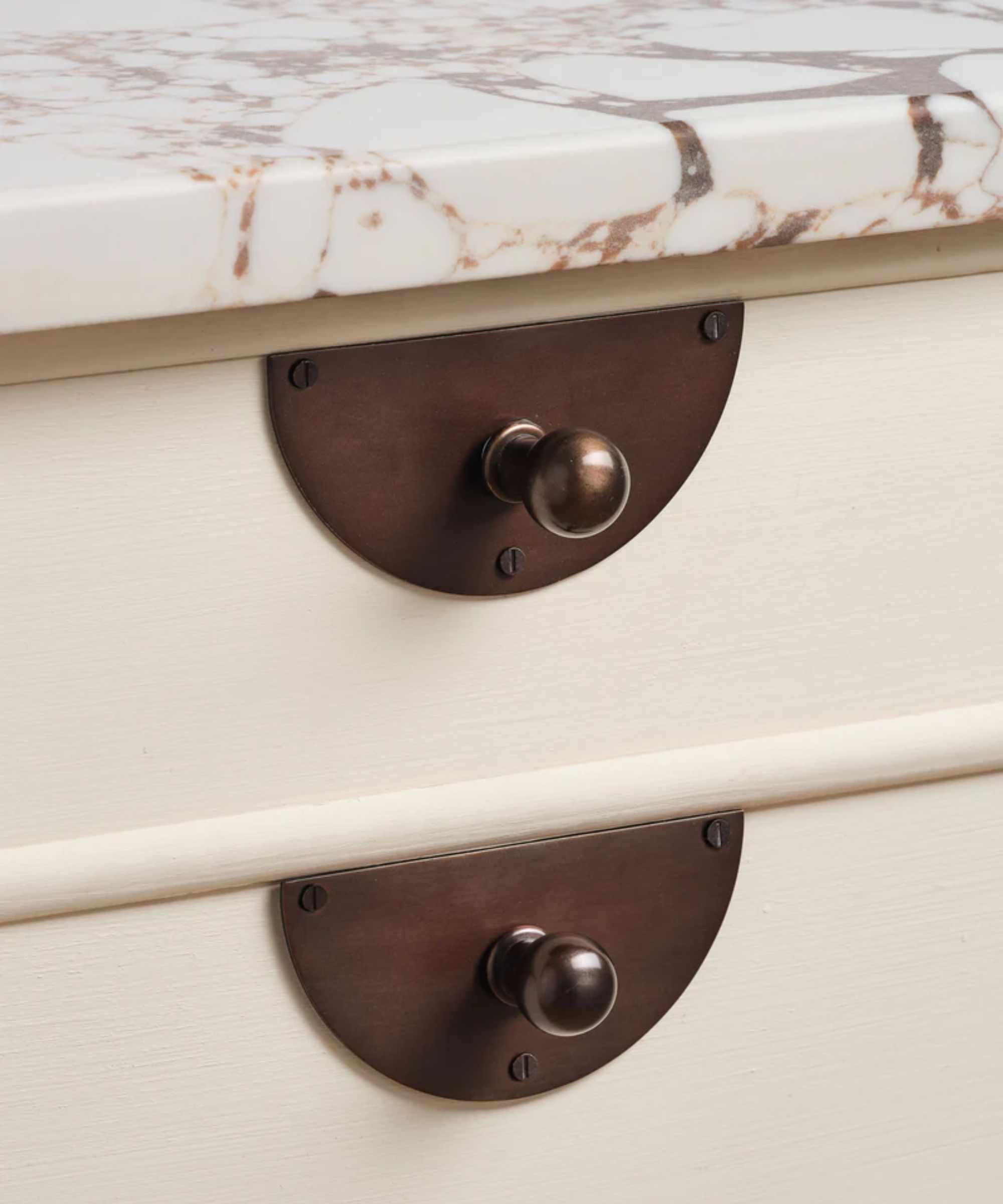 warm white kitchen drawers with a marble countertop and blackened bronze handles with backplates