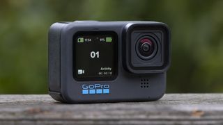En GoPro Hero 11 Black-actionkamera står utomhus på en trästam.