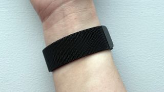 A black-coloured metal mesh watch strap wrapped around a woman's wrist.