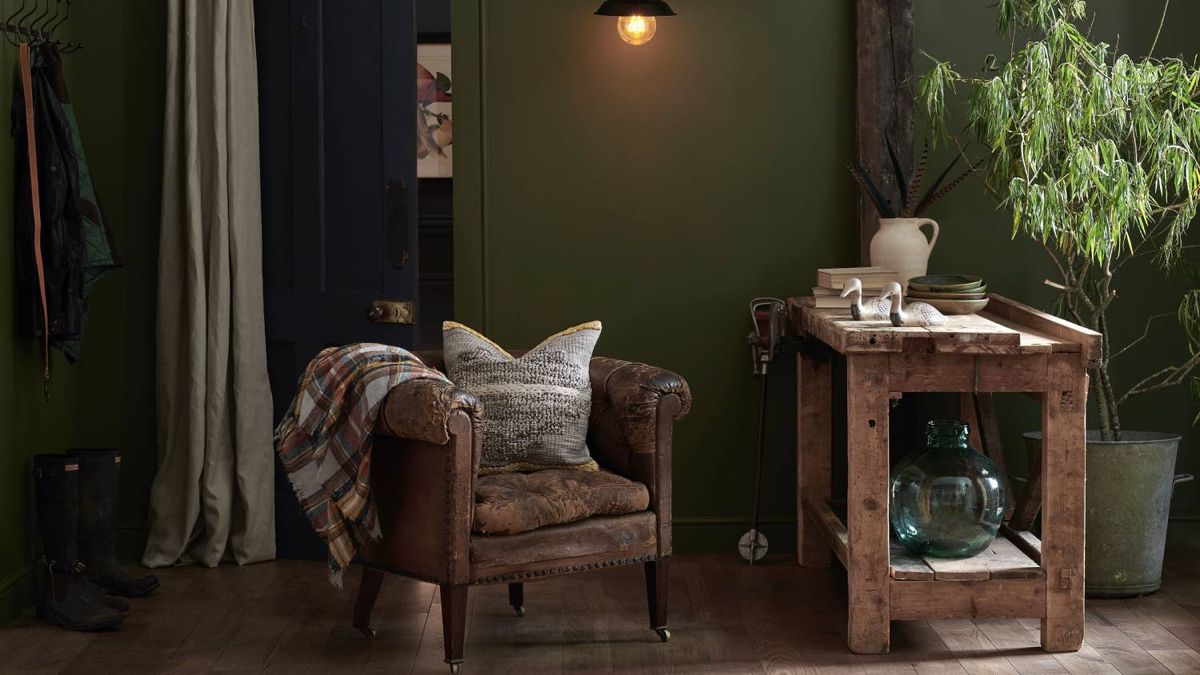 seating area with wooden floor, leather chair, green walls and wooden side table and large plant