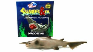 A toy goblin shark in front of its box.