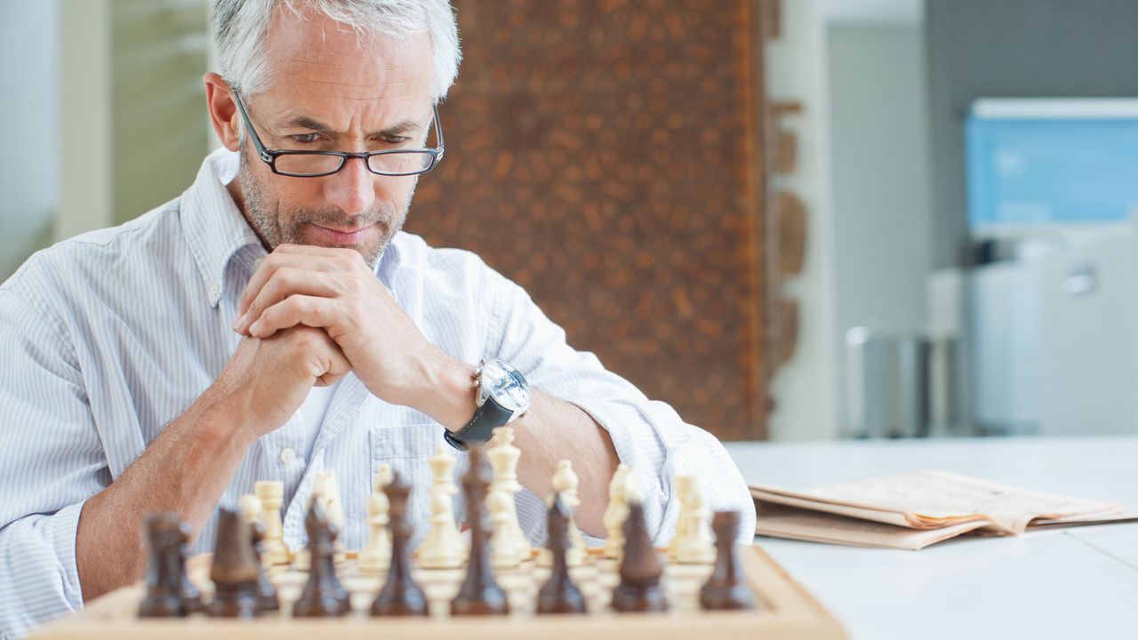 An older man examines a chessboard.