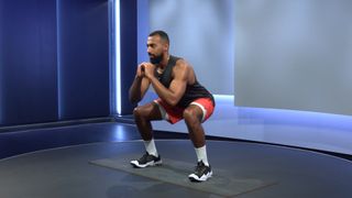 Peloton instructor Jermaine Johnson demonstrates the squat exercise